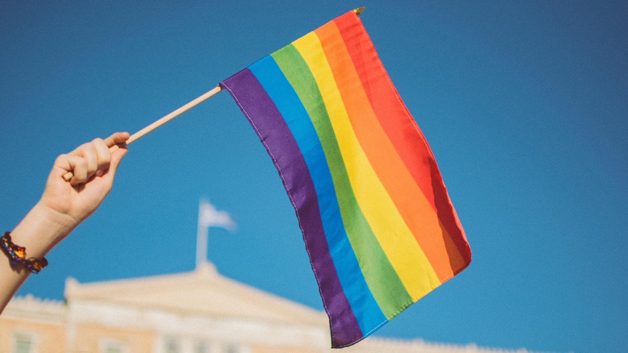 A person waves a rainbow flag.